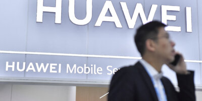 A visitor stands next to the Huawei stand at the Mobile World Congress (MWC). (Photo by Pau BARRENA/AFP).