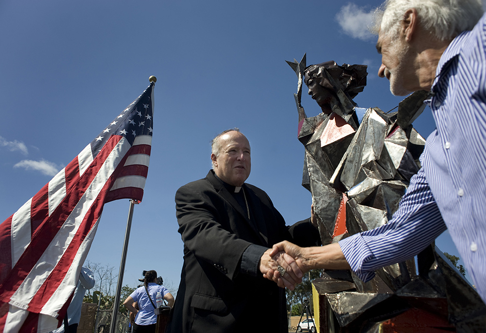 San Diego Bishop Robert McElroy greets artist Jim Bliesner Oct. 5, 2018, next to a miniature replica of a statue Bliesner is creating in honor of immigrants and refugees during a ceremony in San Diego. (CNS/David Maung) San Diego Bishop Robert McElroy greets artist Jim Bliesner Oct. 5, 2018, next to a miniature replica of a statue Bliesner is creating in honor of immigrants and refugees during a ceremony in San Diego. (CNS/David Maung)