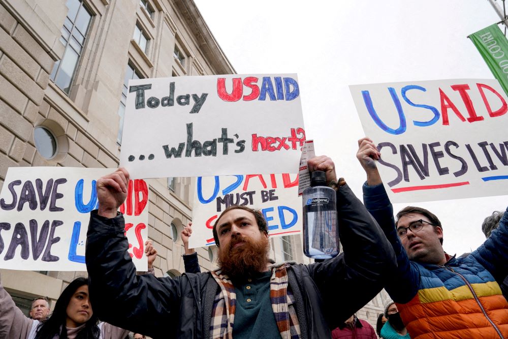 People hold signs protesting USAID cuts.
