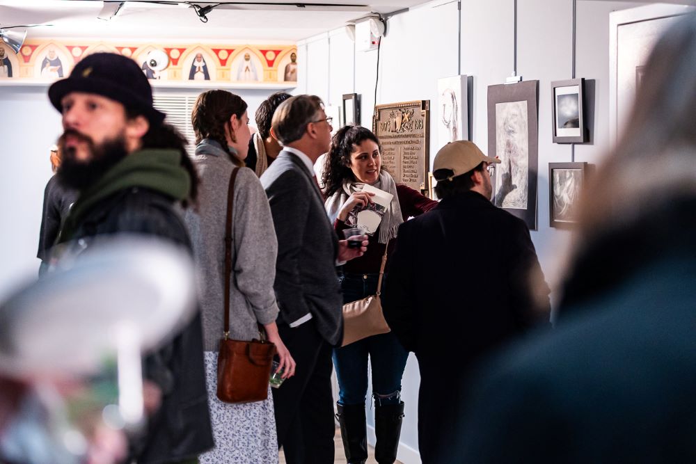 People view artwork on walls.