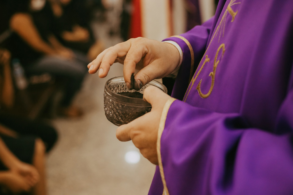 Ash Wednesday, the first day of Lent Someone takes a pinch of ashes from a bowl full of ashes at an Ash Wednesday Mass, the first day of Lent.