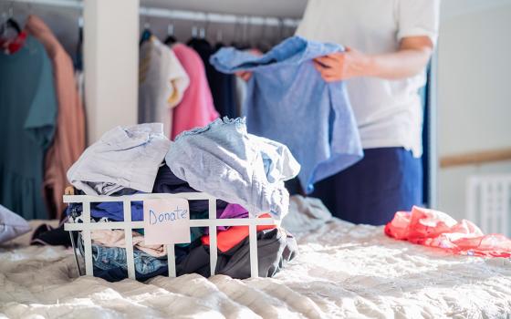 A person clears out clothes from a closet for donation (Dreamstime/Oksana Krasiuk)