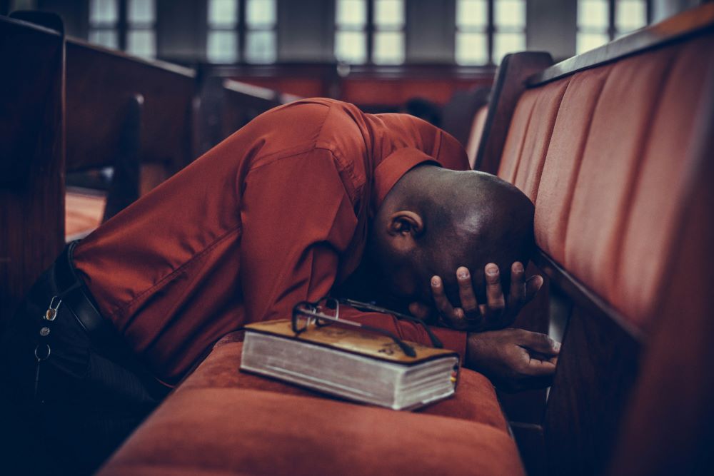 Man with head down on chairs, praying Man with head down on chairs, praying
