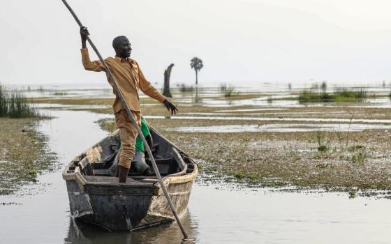 John Gafabusa, custodian of the Mutyona natural sacred site near Buliisa, Uganda, points at a water covered sacred site on Lake Albert at the Karakaba landing site, Aug. 3, 2023.
